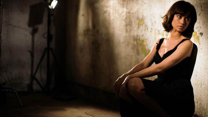 Olga Kurylenko Sitting Pose in Black Dress