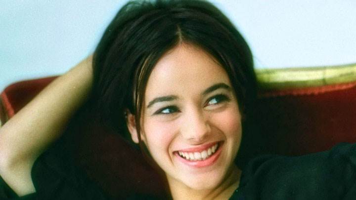 Alizee Jacotey Laughing And Sitting On A Sofa