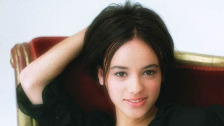 Alizee Jacotey Sitting On Red Sofa In Black Dress